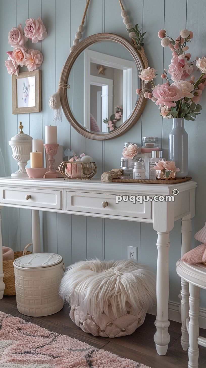 Vanity table with decorative items, candles, and flower arrangements, a round mirror hanging above, and a fluffy stool underneath.
