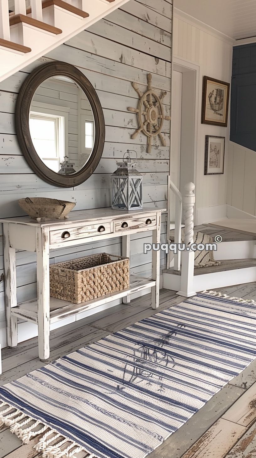 Rustic coastal-themed entryway with a weathered wooden console table, round mirror, nautical decor, woven basket, lantern, and striped rug.