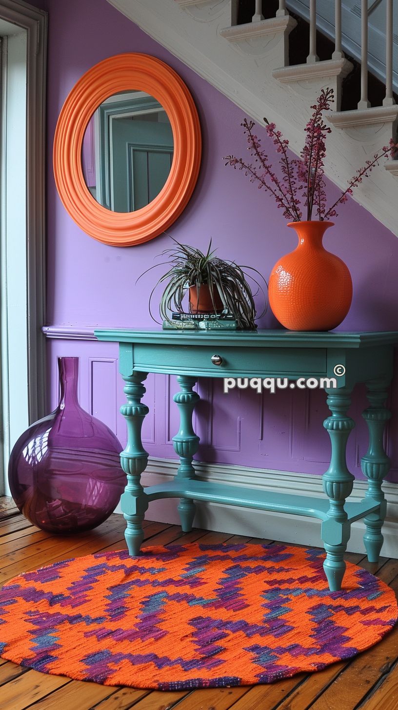 Purple-walled interior with a turquoise console table, orange vase, orange-framed mirror, and colorful round rug.