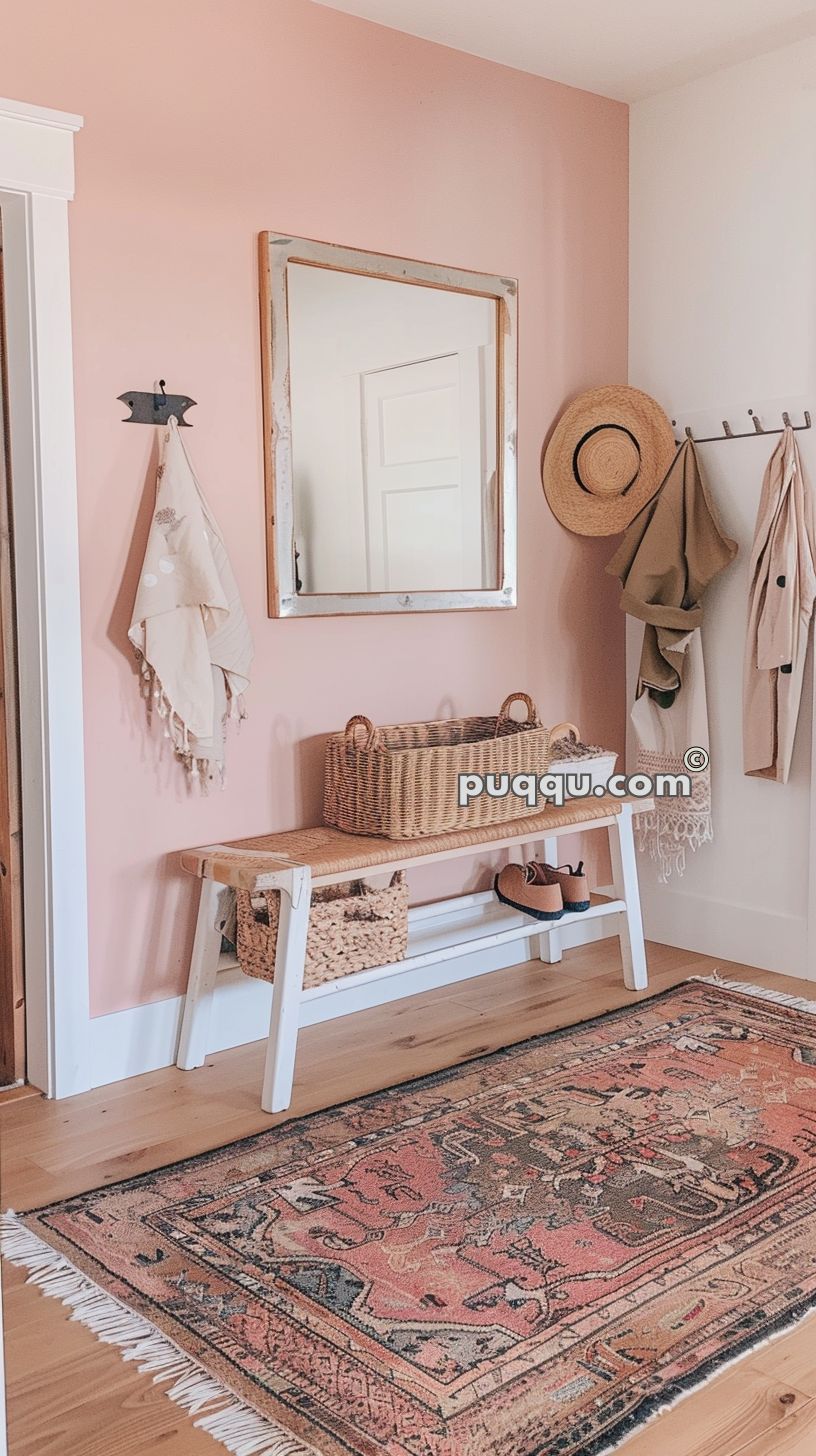 Entryway with a pink accent wall, a large mirror, a wooden bench with woven baskets, hanging hats and coats, and a patterned rug.