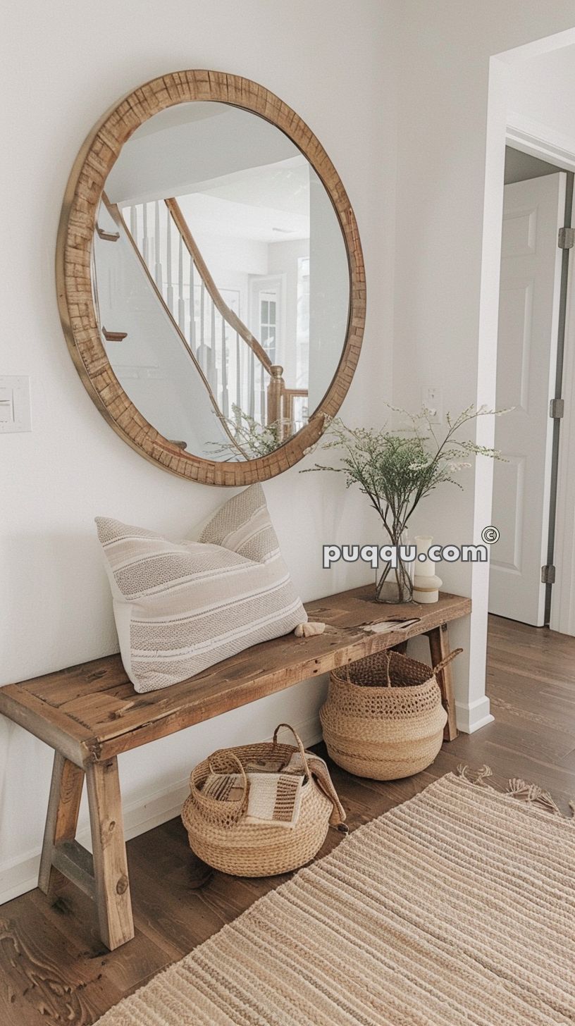Entryway with a large round mirror, wooden bench, decorative pillow, woven baskets, and a vase with greenery.