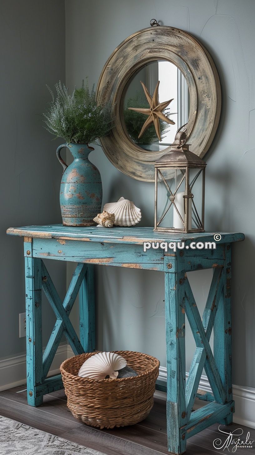 Rustic blue wooden table with seashell decor, a potted plant, a lantern, and a round wooden mirror with a starfish in the center.