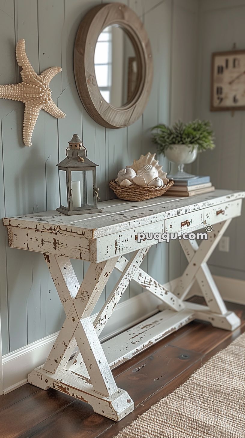 Rustic entryway with a distressed white console table, decorated with a lantern, a basket of seashells, books, and potted plant, a round wooden mirror, and a starfish wall decoration.