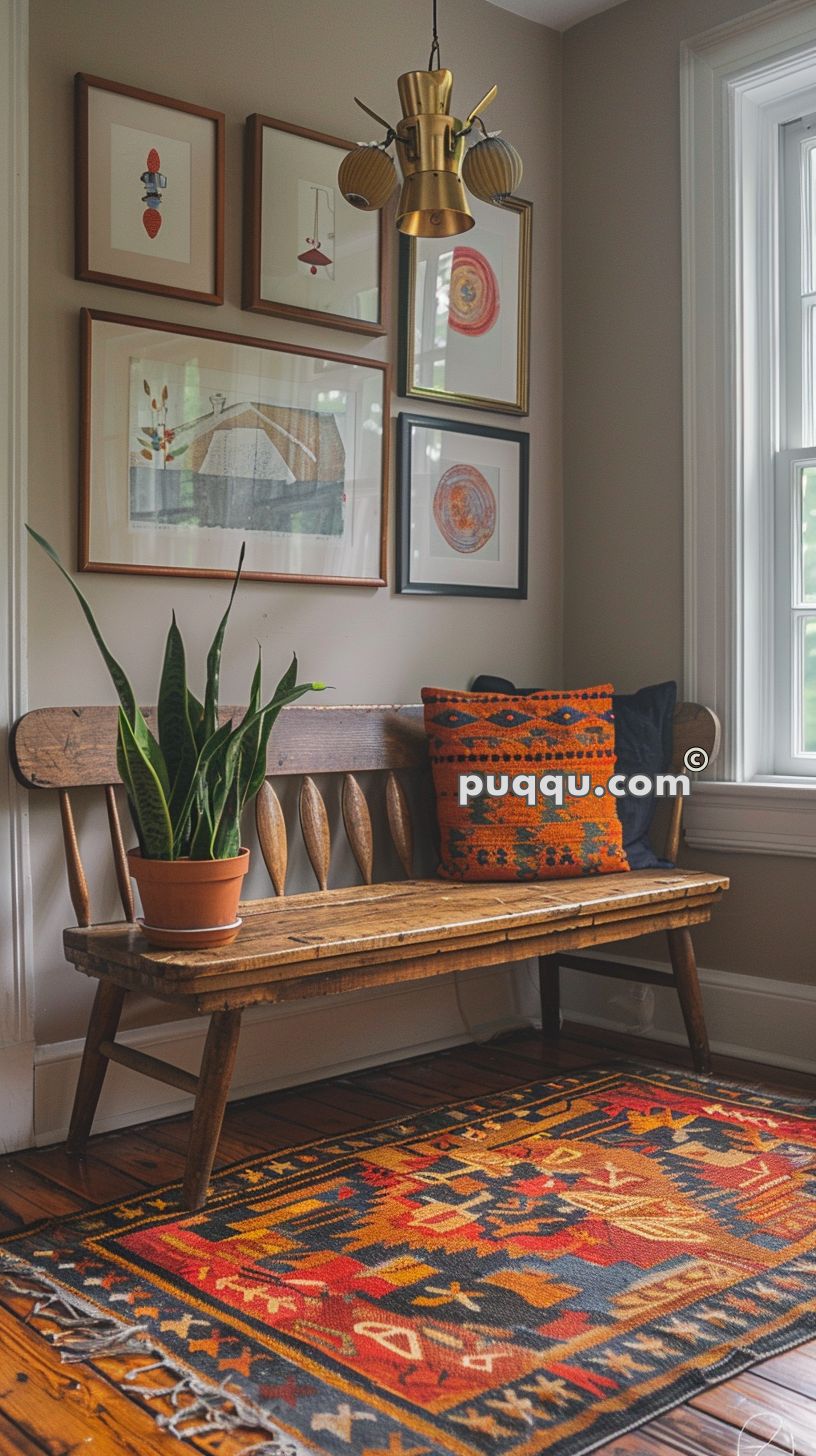A cozy interior corner featuring a wooden bench with an orange patterned cushion, a potted plant, a colorful area rug, and framed artwork on the wall.