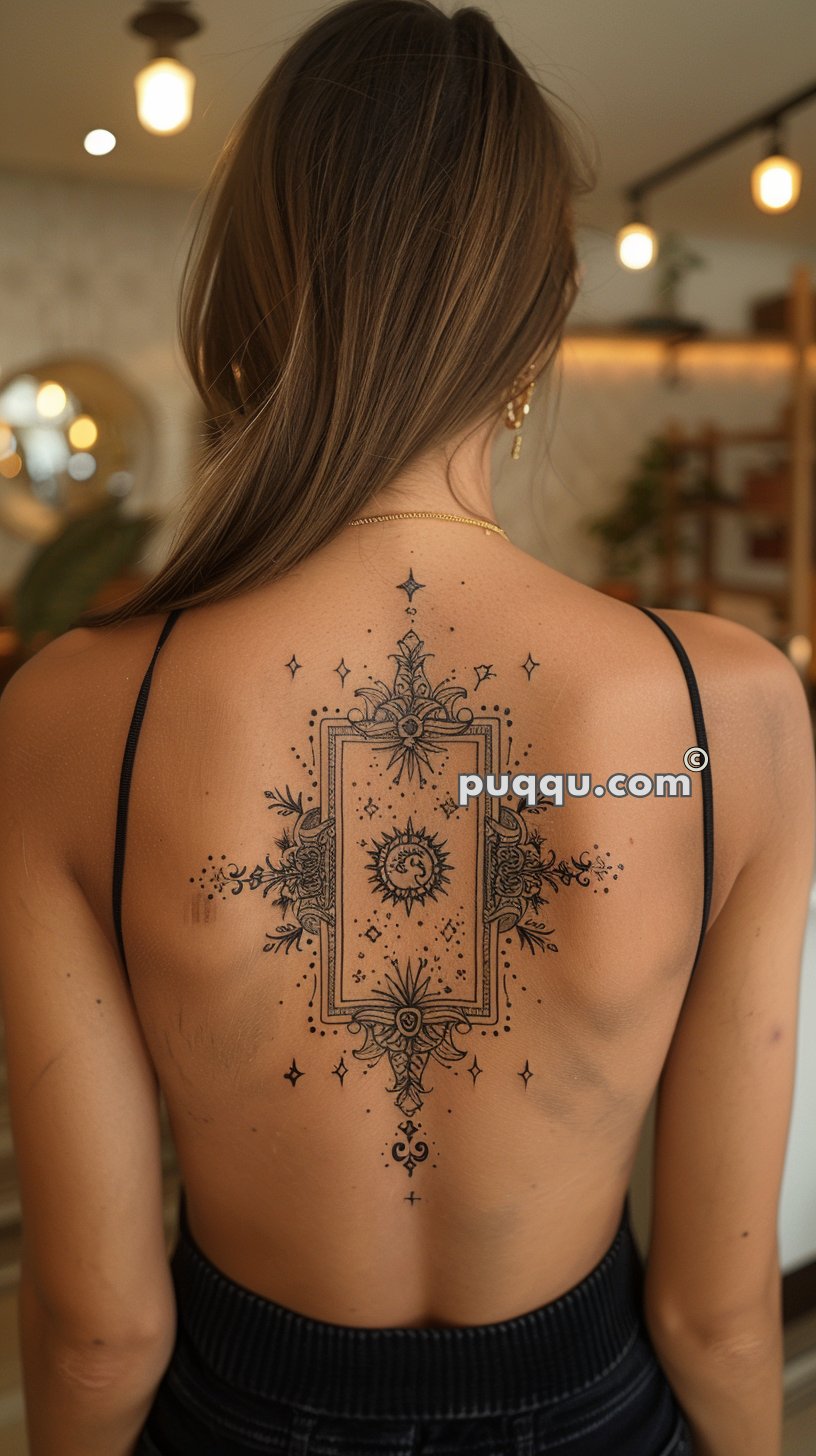 Woman with intricate black ink tattoo on her back featuring celestial and ornamental designs, wearing a strappy top.