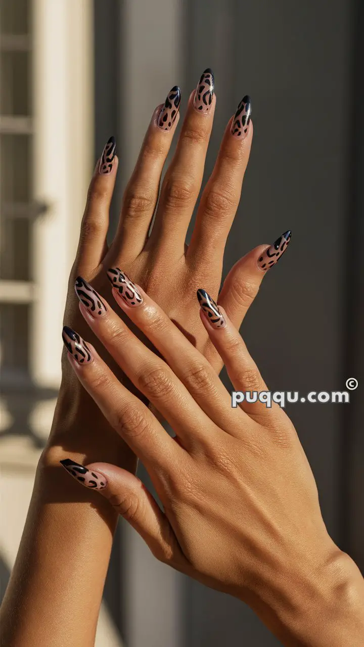 Hands with long, pointed nails featuring a leopard print design against a blurred background.