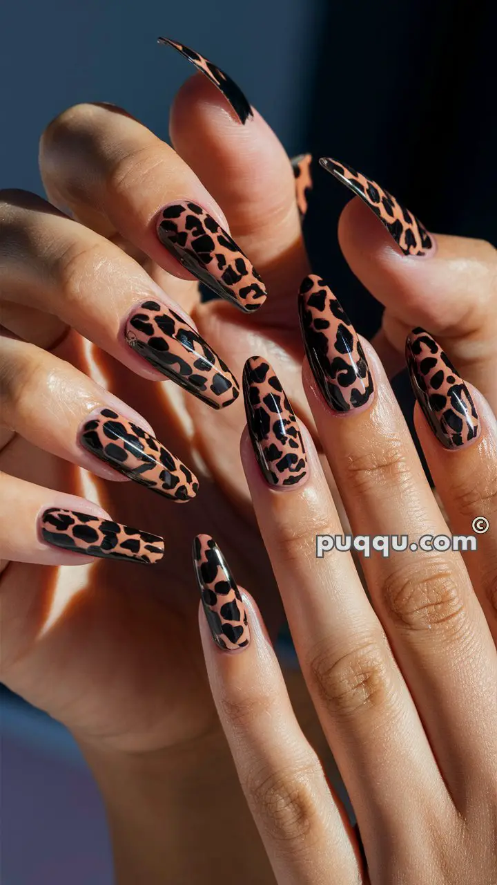 Close-up of hands with long, almond-shaped nails featuring a glossy, leopard print design on a light brown base.