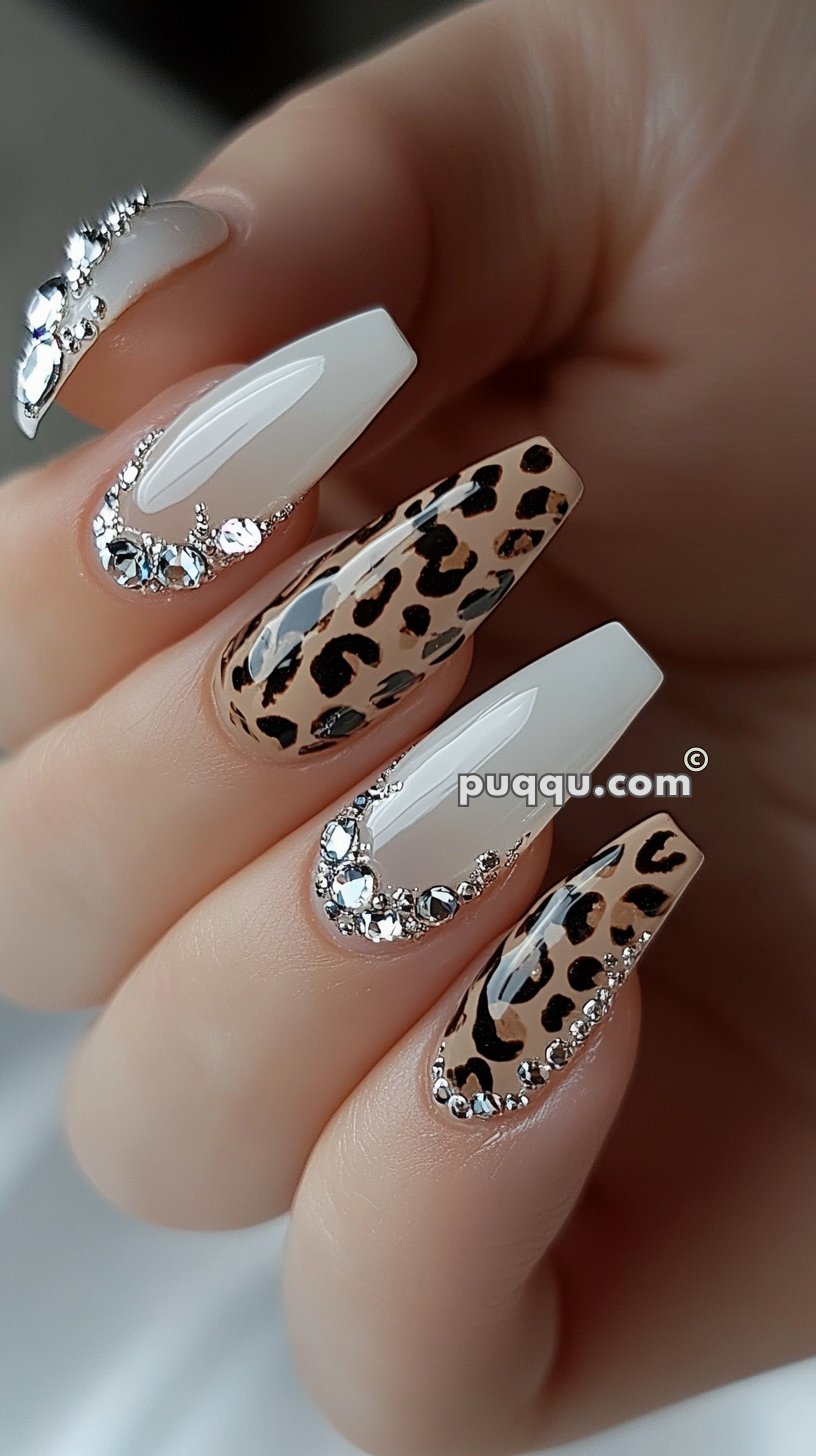 White and leopard print nails adorned with rhinestones.