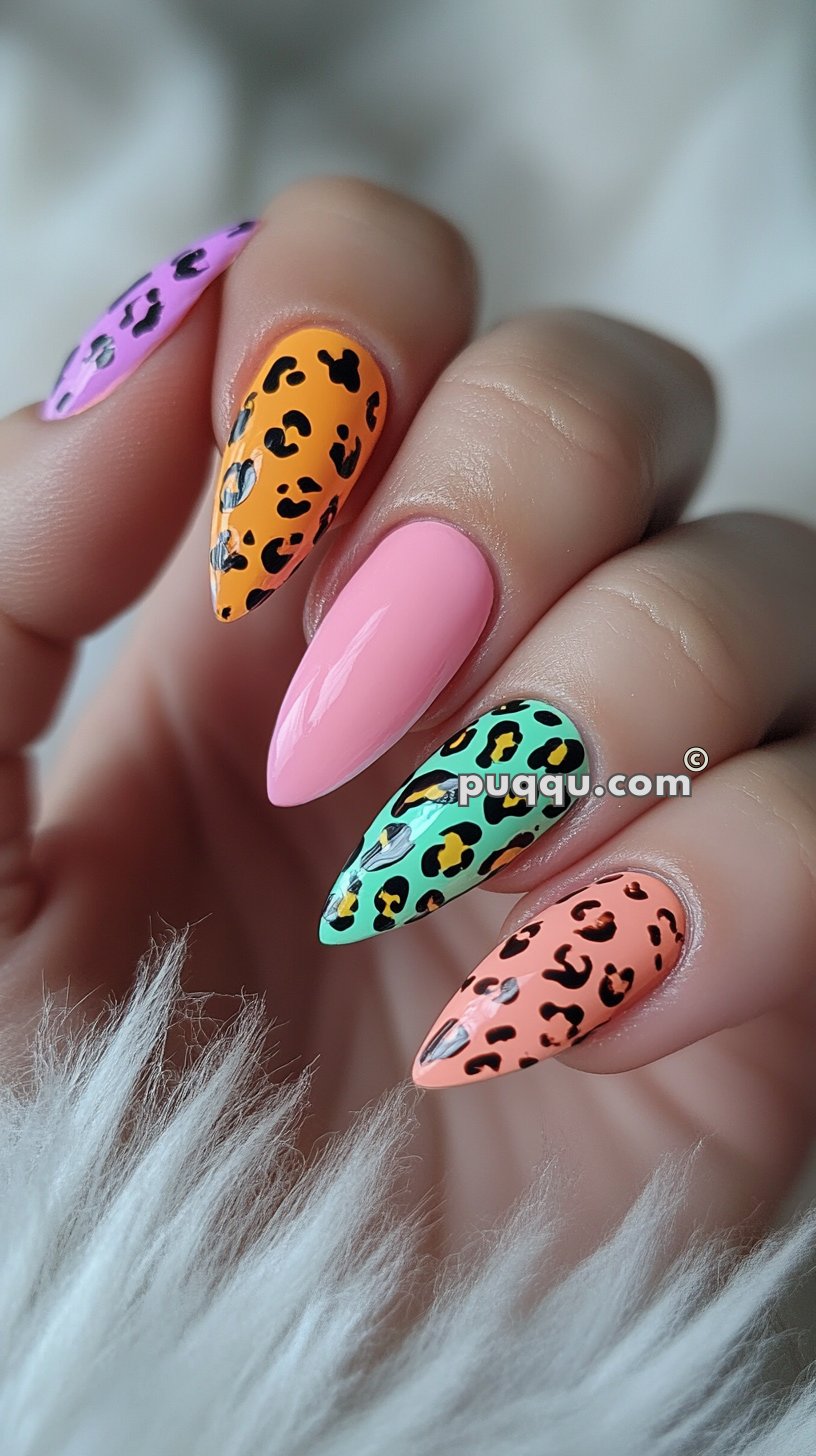 Colorful leopard print nail art on long, almond-shaped nails featuring pink, orange, green, and peach designs.