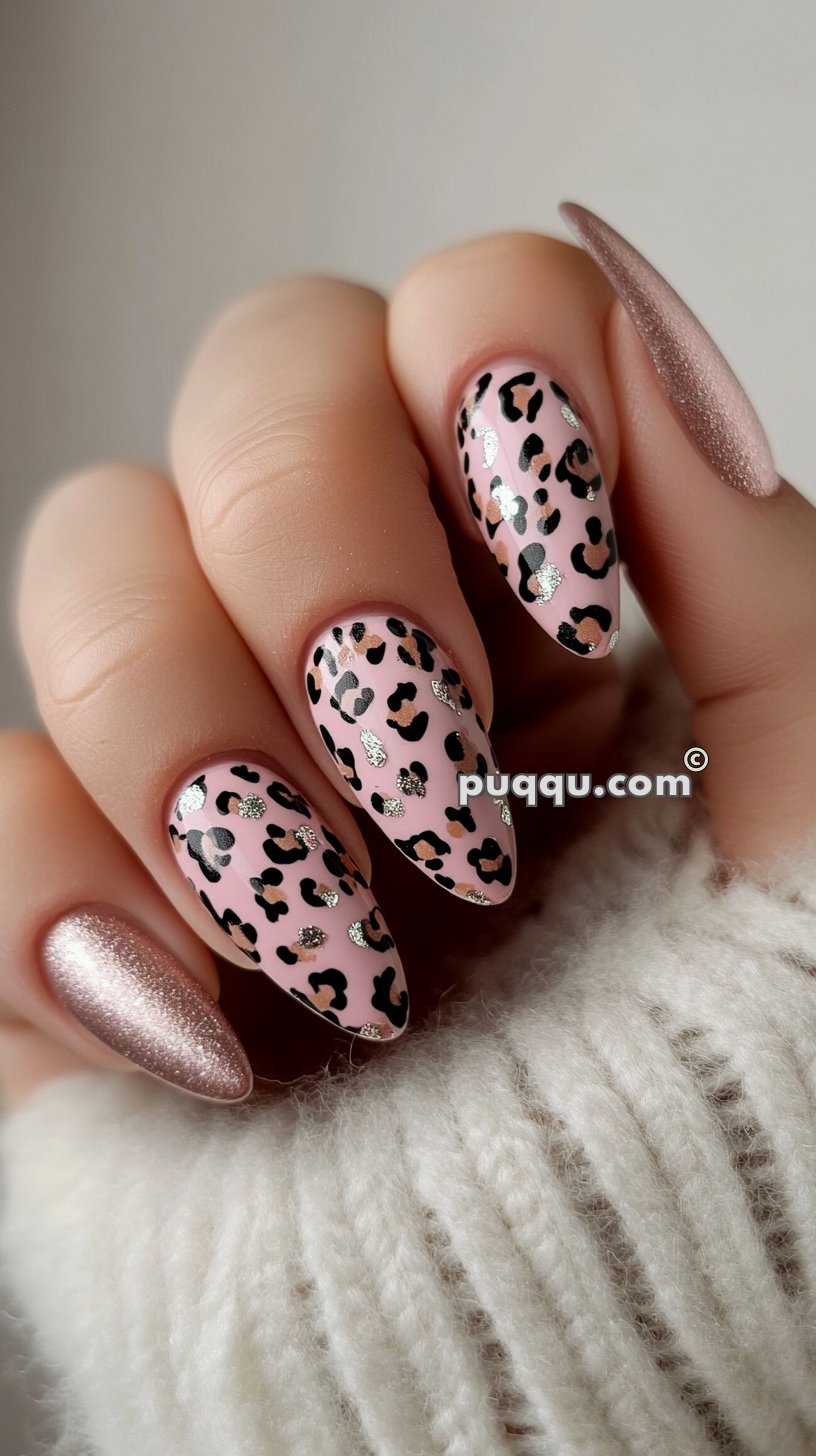 Pink nails with black and silver leopard print accents, alongside a sparkly rose gold nail, held by a hand on a white, fuzzy sweater.