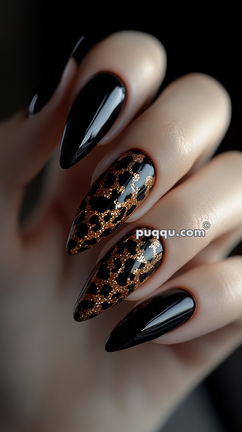 Close-up of a hand with long, stiletto-shaped nails featuring a black base with gold glitter leopard print design.