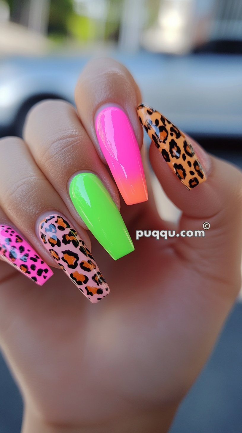 Close-up of a hand with long, coffin-shaped nails featuring bright neon and leopard print designs.