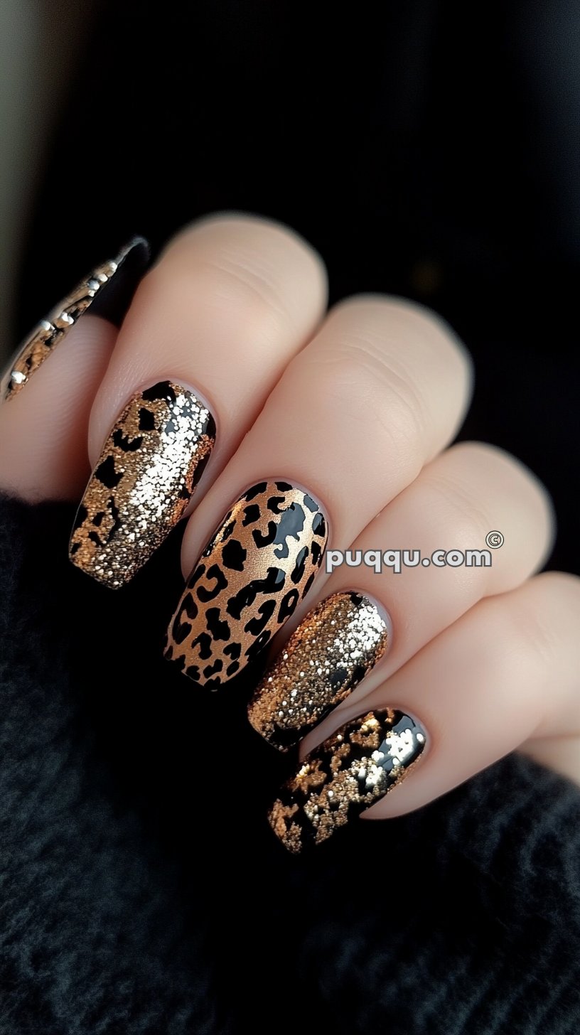 Close-up of a hand with long nails featuring gold glitter and leopard print nail art on a black background.