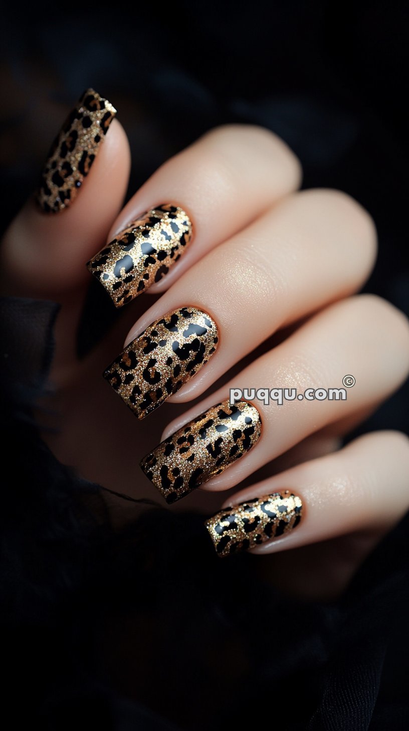 Hand with long nails featuring a gold and black leopard print design.