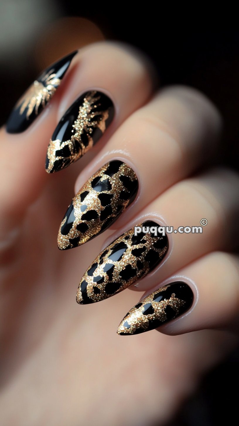 Black stiletto nails with intricate gold glitter patterns resembling leopard spots and decorative leaves.