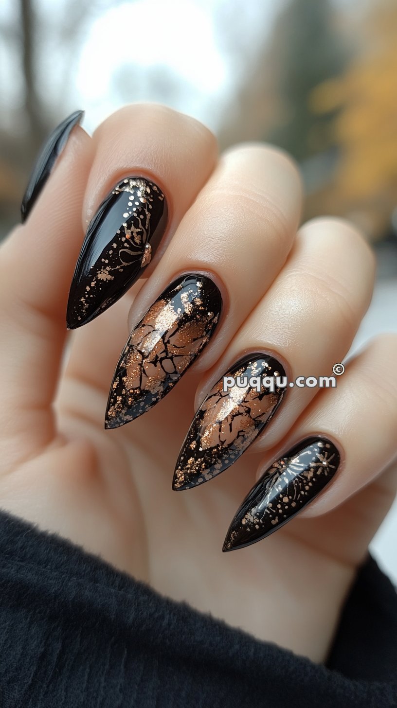 Black stiletto nails with copper foil accents and intricate gold designs.