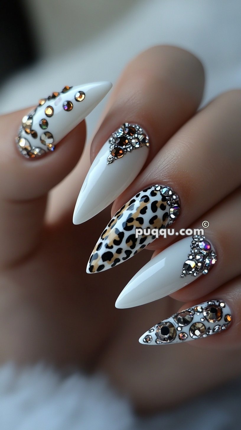 White stiletto nails with leopard print and rhinestone embellishments.