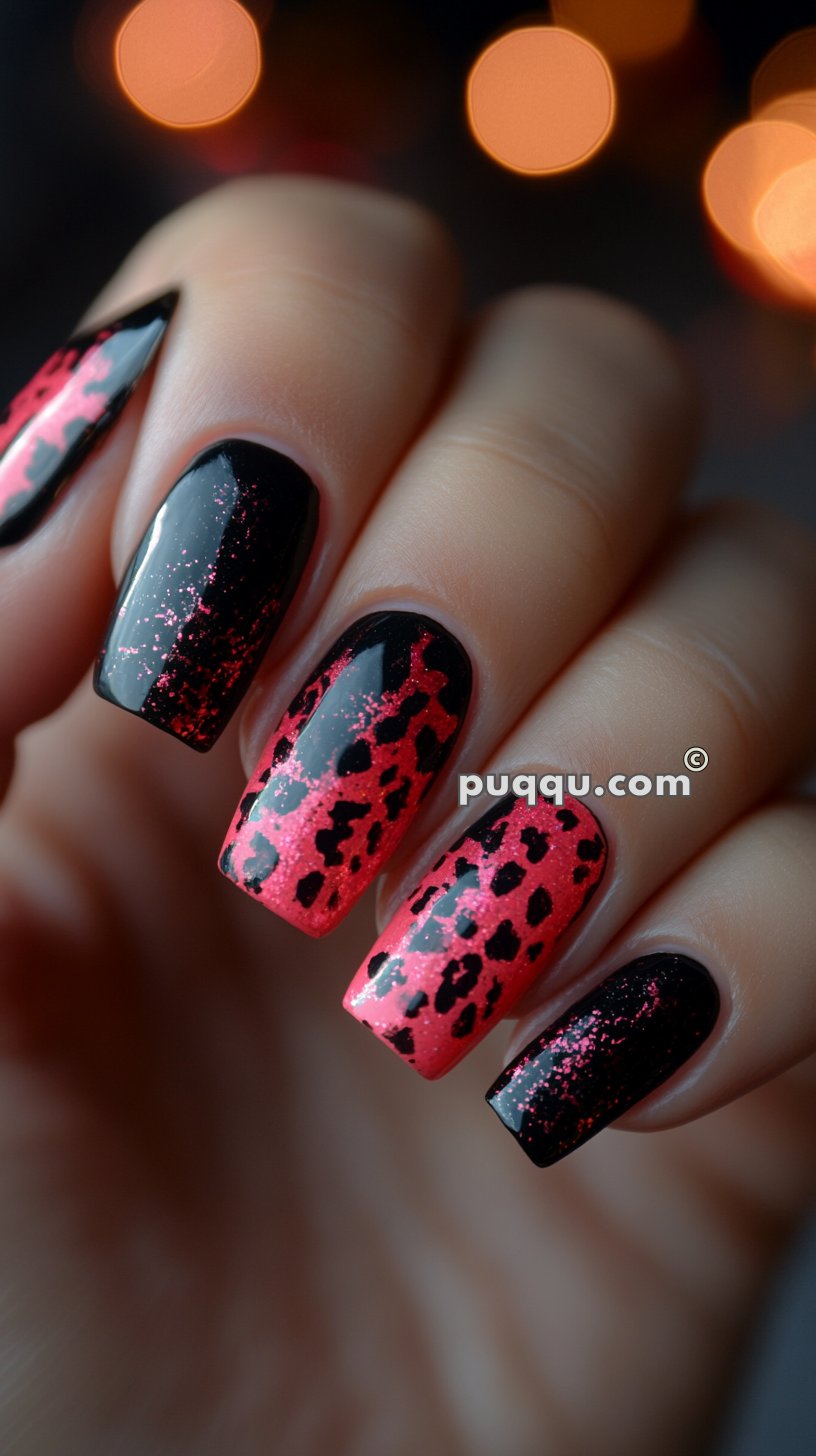 Close-up of a hand with long nails painted in a black and red leopard print design with glitter.