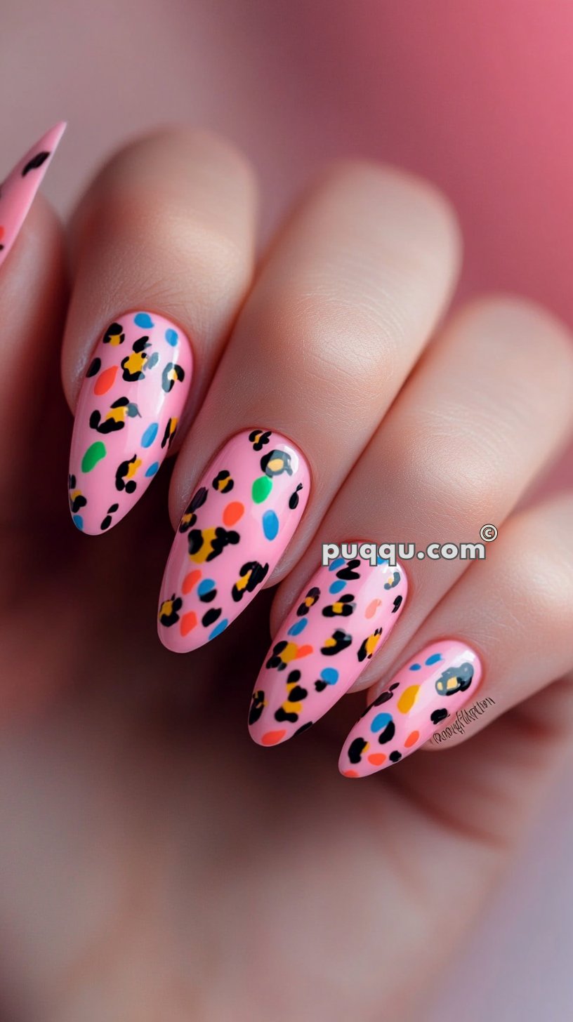 Close-up of a hand with long, almond-shaped pink nails decorated with colorful leopard print designs.