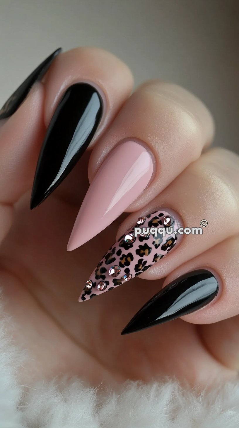 Long stiletto nails with black, pink, and leopard print designs, adorned with rhinestones.