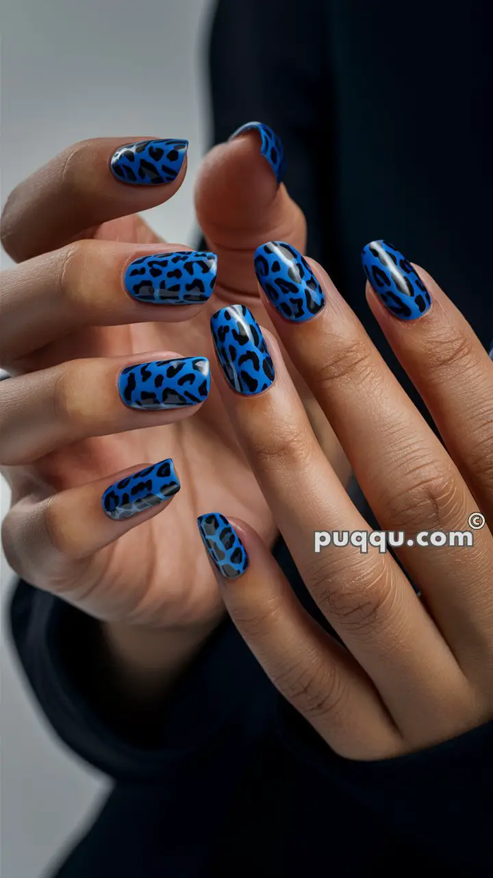 Hands with blue and black leopard print nail art.