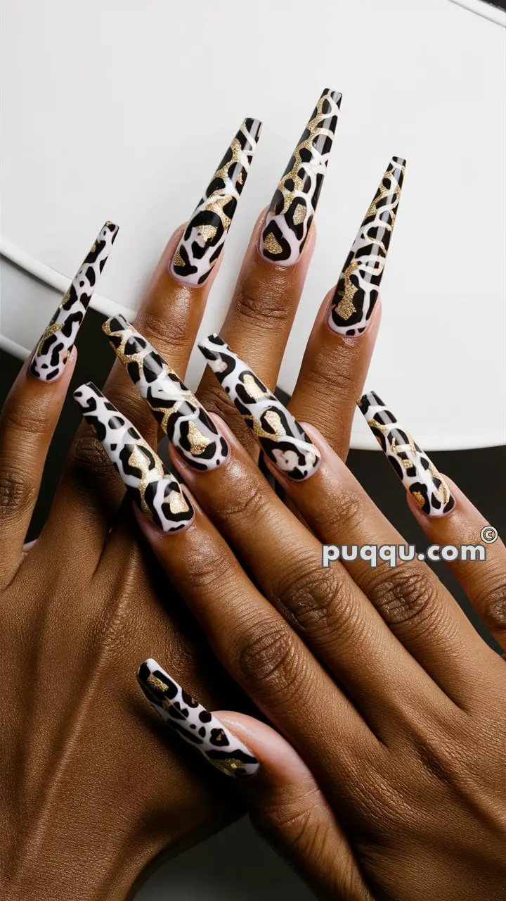 Hands with long stiletto-shaped nails featuring a leopard print design with black, white, and gold elements.