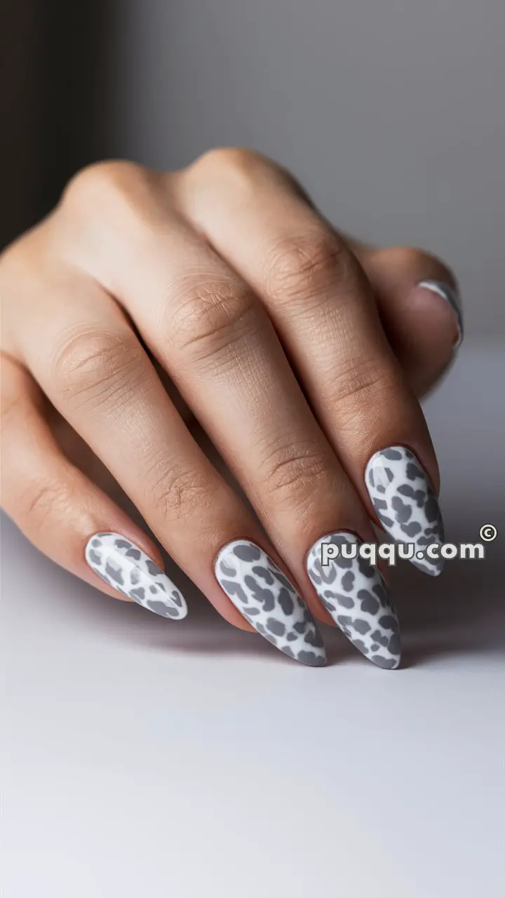 Hand with long nails featuring a white and gray leopard print design.