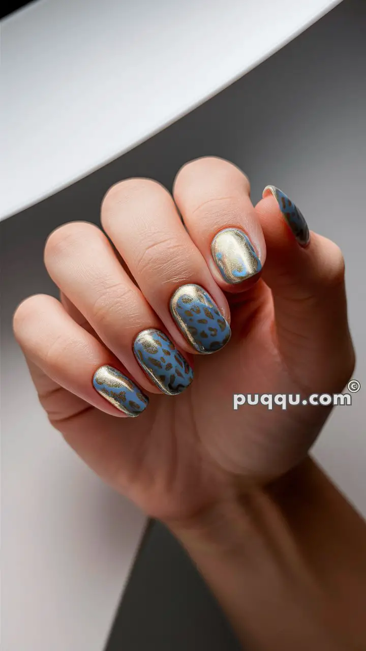 Close-up of a hand with gold and blue leopard print nail art.