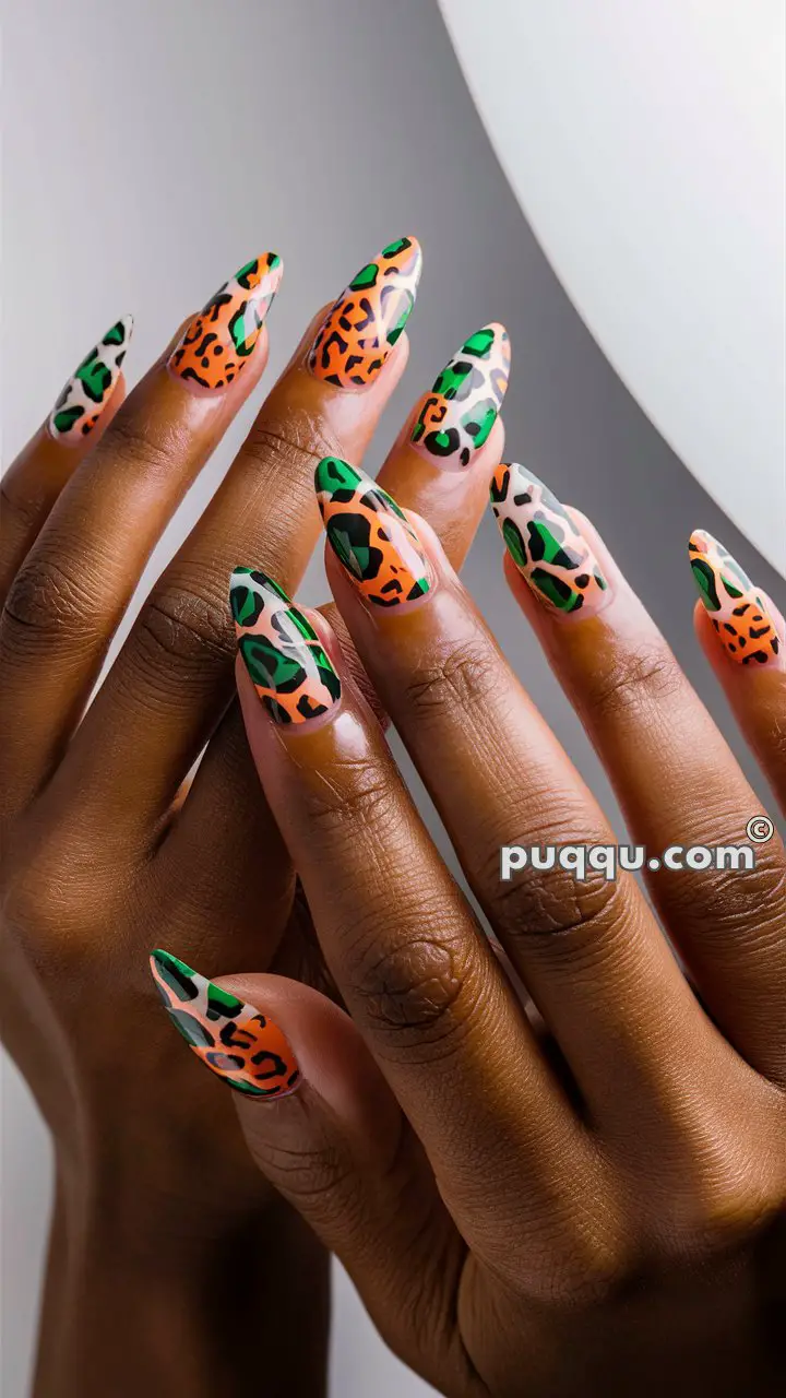 Close-up of hands with long nails featuring vibrant leopard print nail art in orange, green, and black.