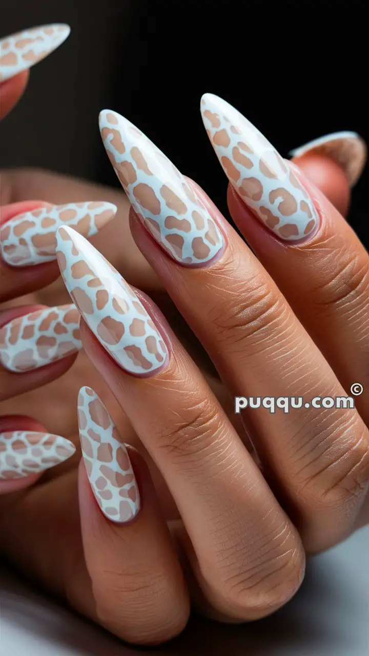 Close-up of hands with long, almond-shaped nails featuring a white and beige leopard print design against a natural background.