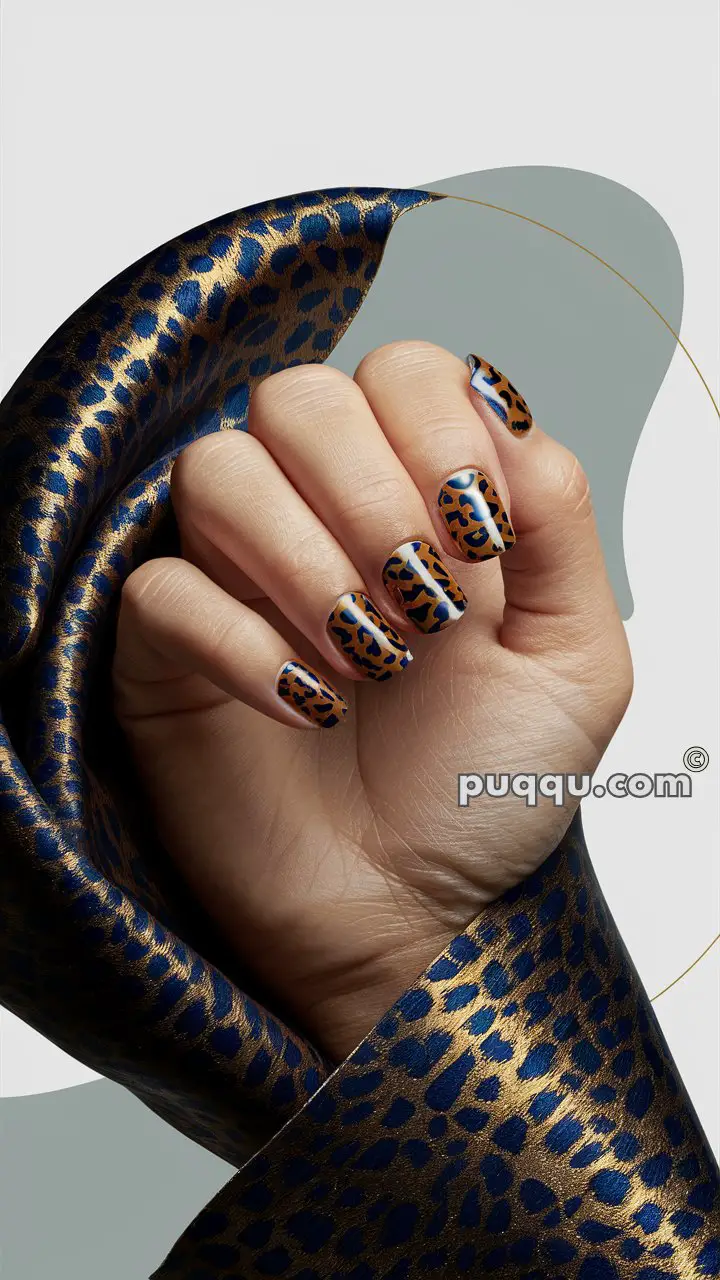 Hand with leopard print nail art holding a blue and gold leopard print fabric.