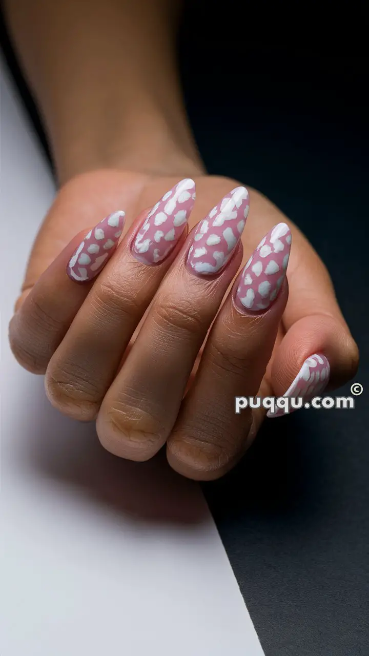 Hand with long, almond-shaped nails painted in pink with white cloud patterns.