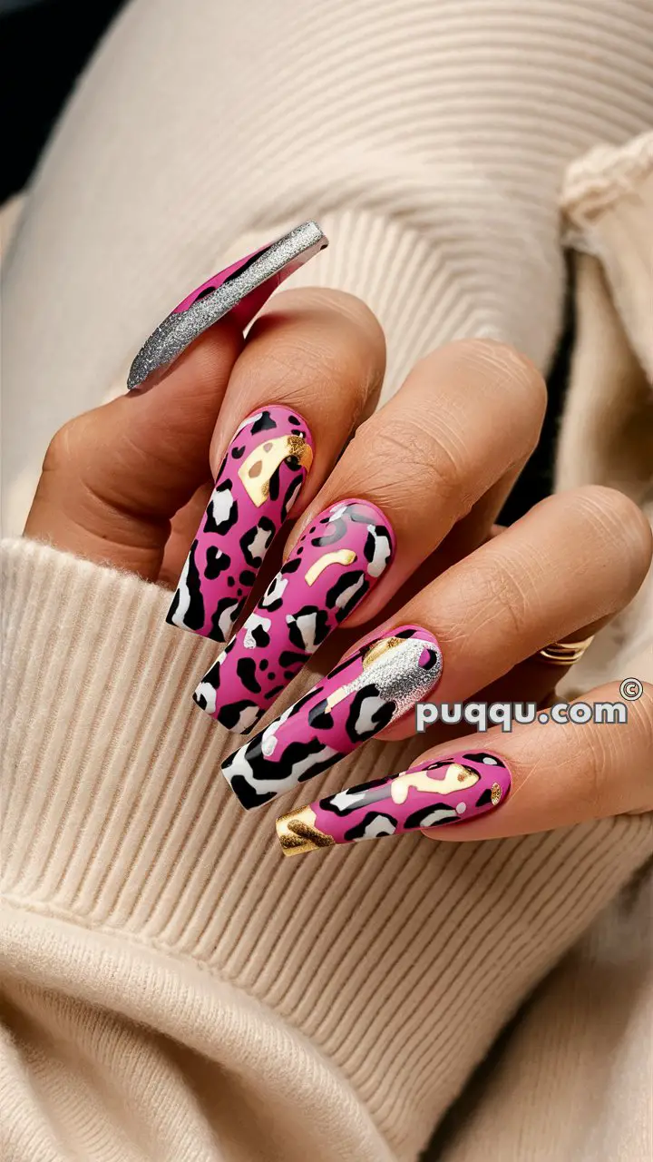 Hand with long pink nails featuring black and white leopard print design and gold accents.