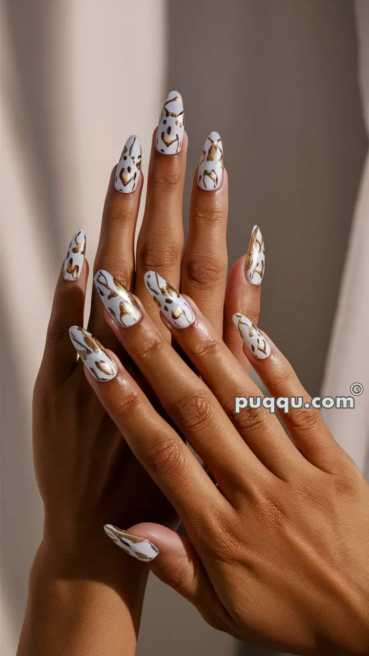 Hands with long, almond-shaped nails featuring white nail polish with gold abstract designs.