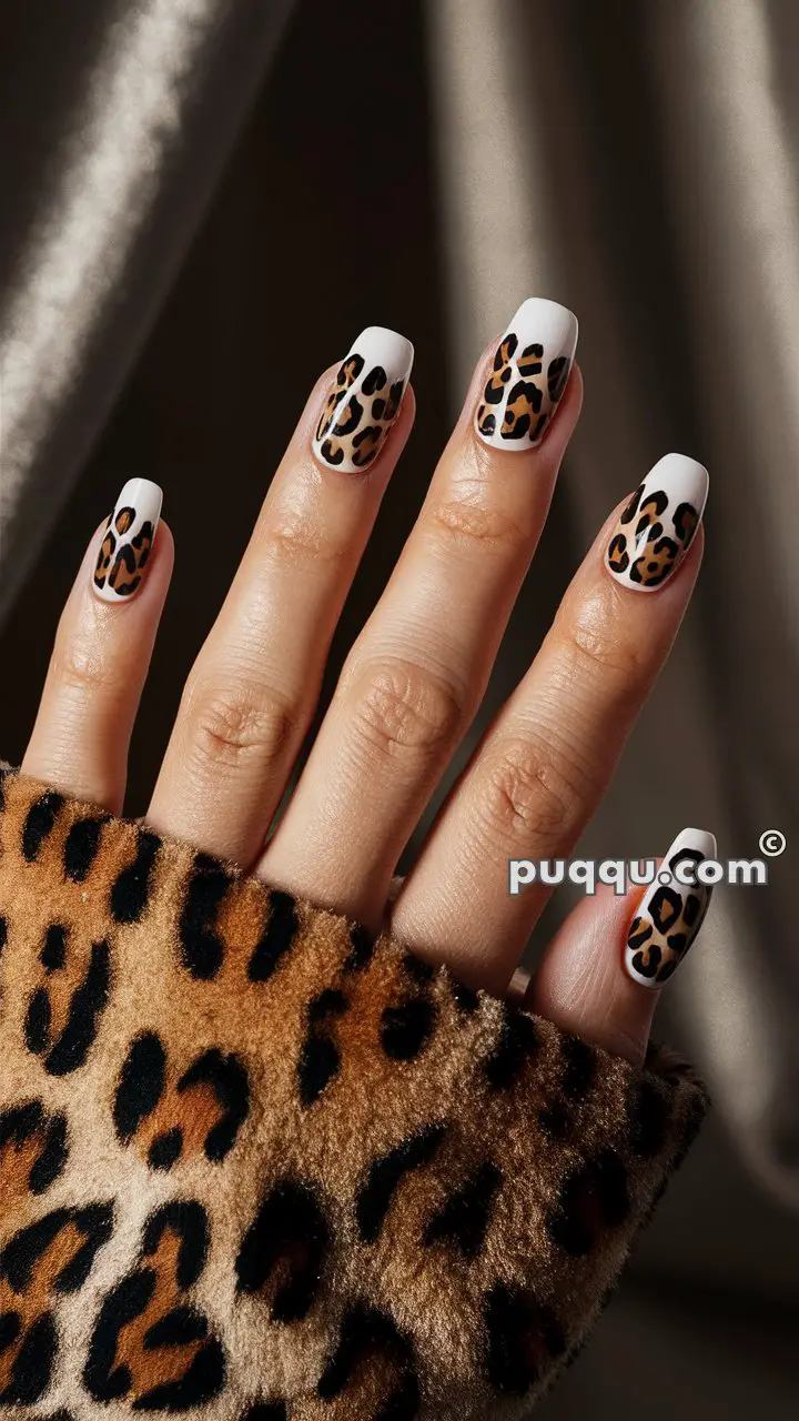 A hand with leopard print nails matching a leopard print clothing sleeve.