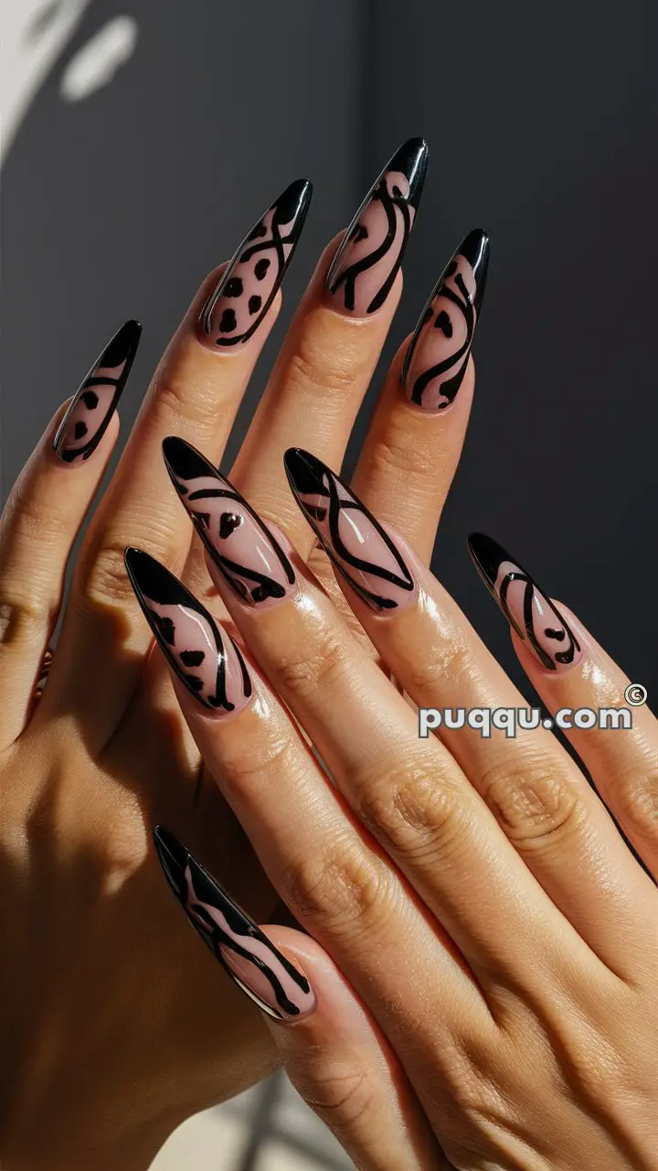 Close-up of hands with long, almond-shaped nails featuring a nude base and intricate black abstract designs.