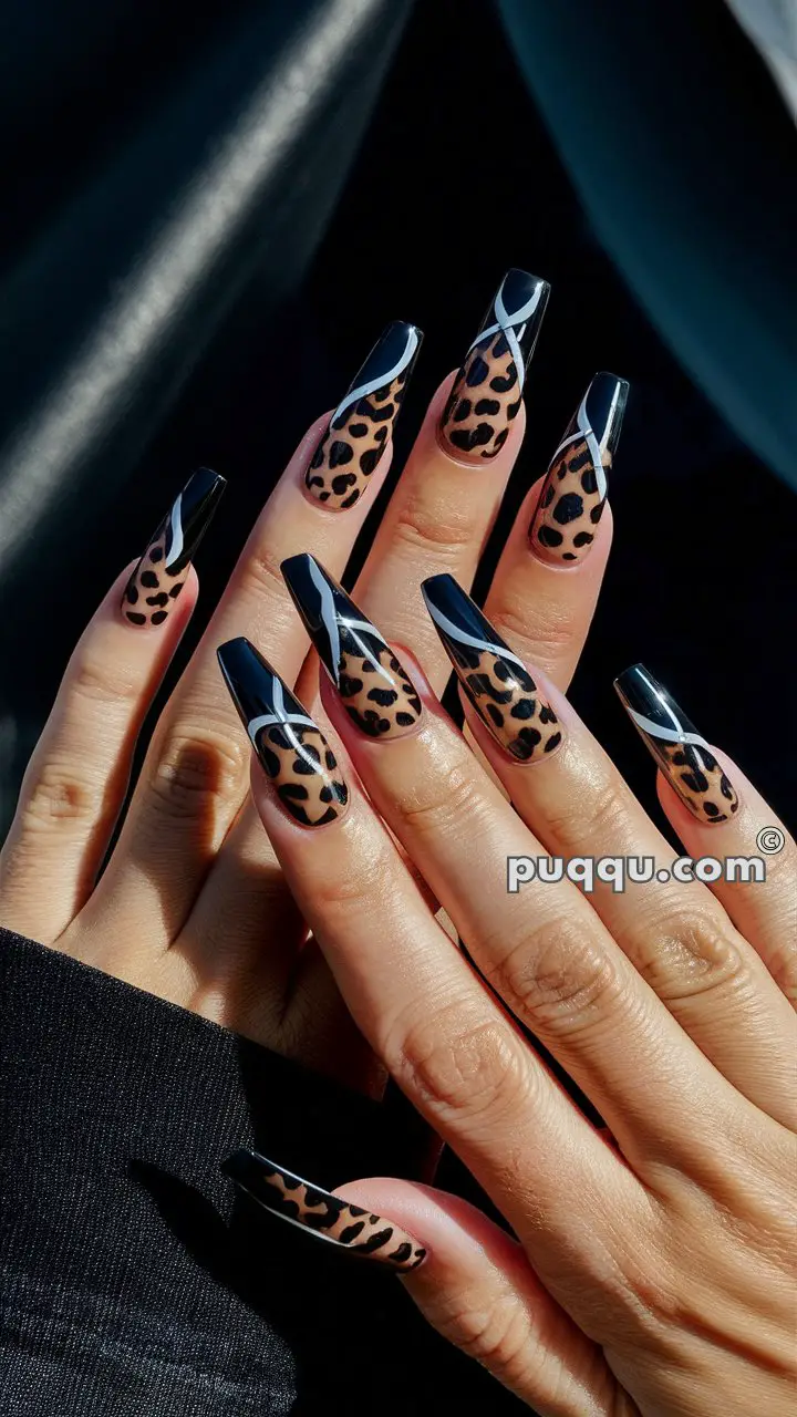 Hands with long acrylic nails featuring a leopard print design and black tips with white accents.