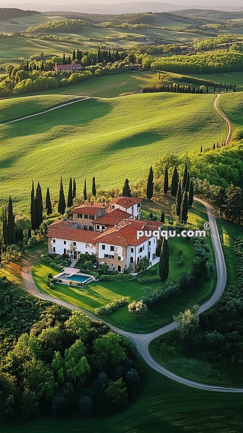 Aerial view of an Italian villa with red-tiled roofs and a swimming pool, surrounded by greenery, trees, and winding roads in a hilly landscape.