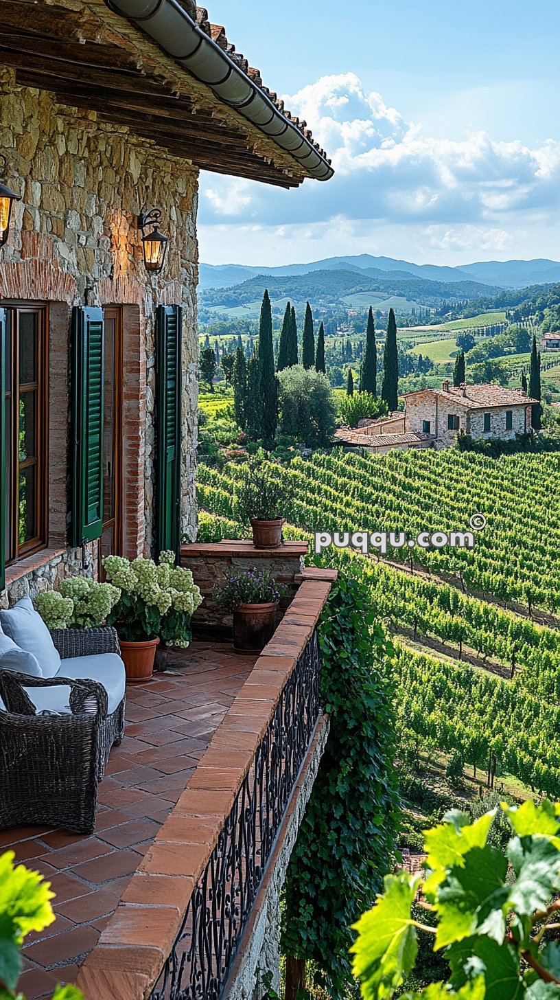 Stone house balcony overlooking a lush vineyard and rolling hills in the background.