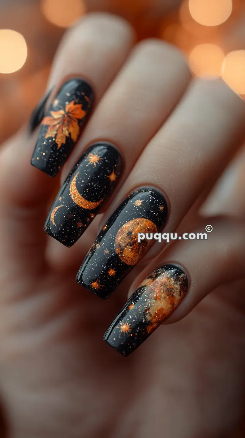 Black glittery Halloween-themed nails with orange celestial designs including stars, moons, and leaves.