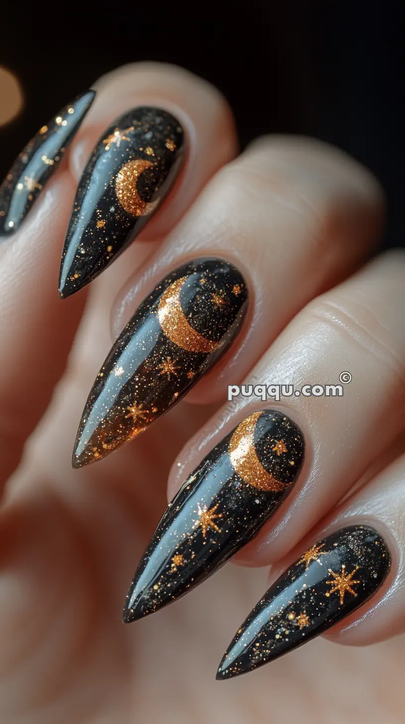 Close-up of nails with black and gold crescent moon and star designs.