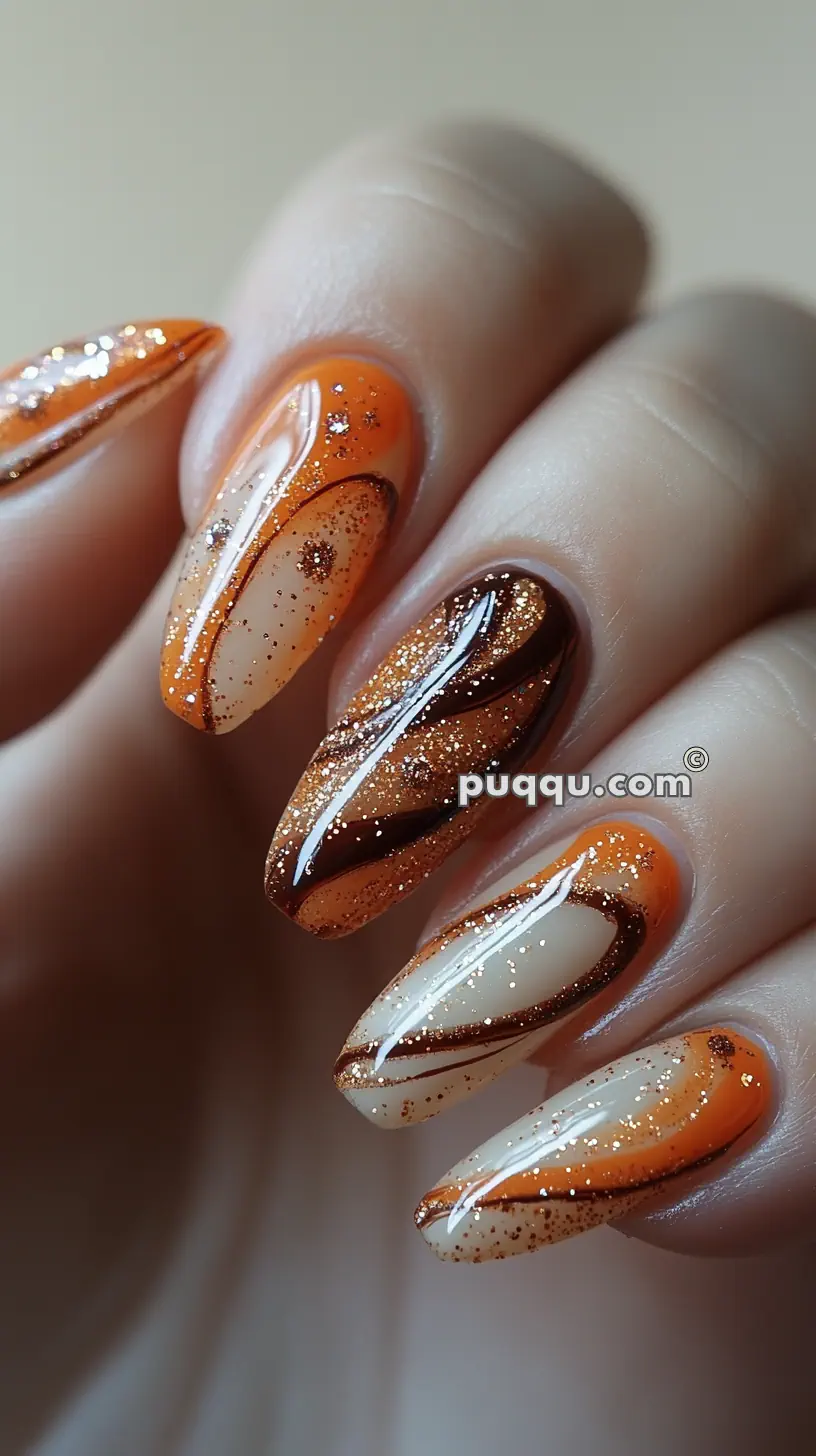 Orange, brown, and beige abstract swirl manicure with glitter on almond-shaped nails.