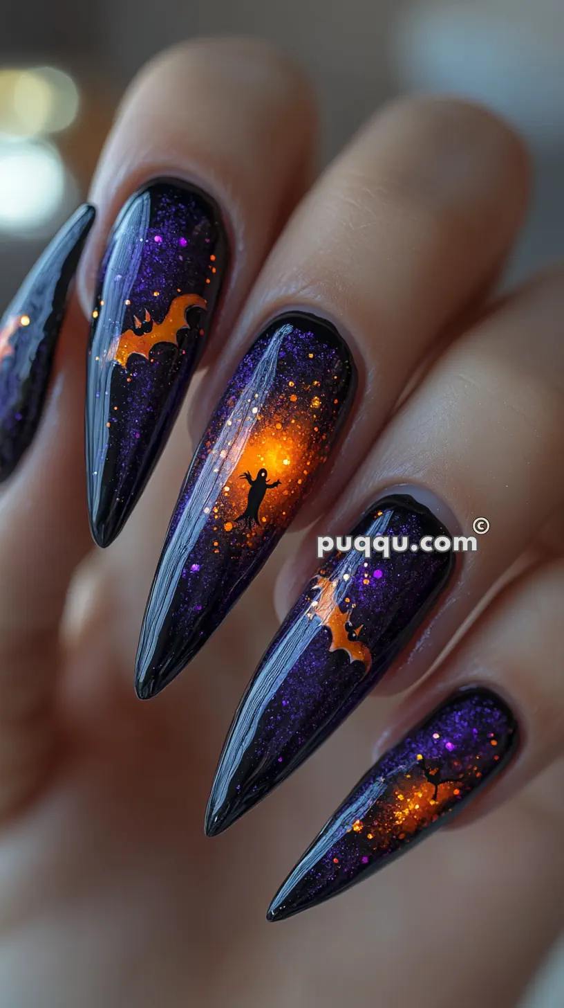 Close-up of Halloween-themed stiletto nails with dark purple glitter, black bats, orange accents, and a ghost silhouette.