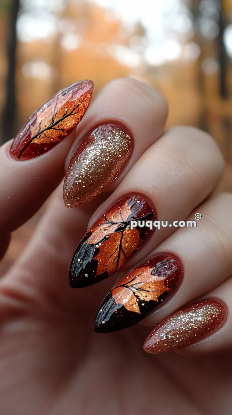 Nails with an autumn-themed design featuring intricate orange leaf patterns and gold glitter accents.