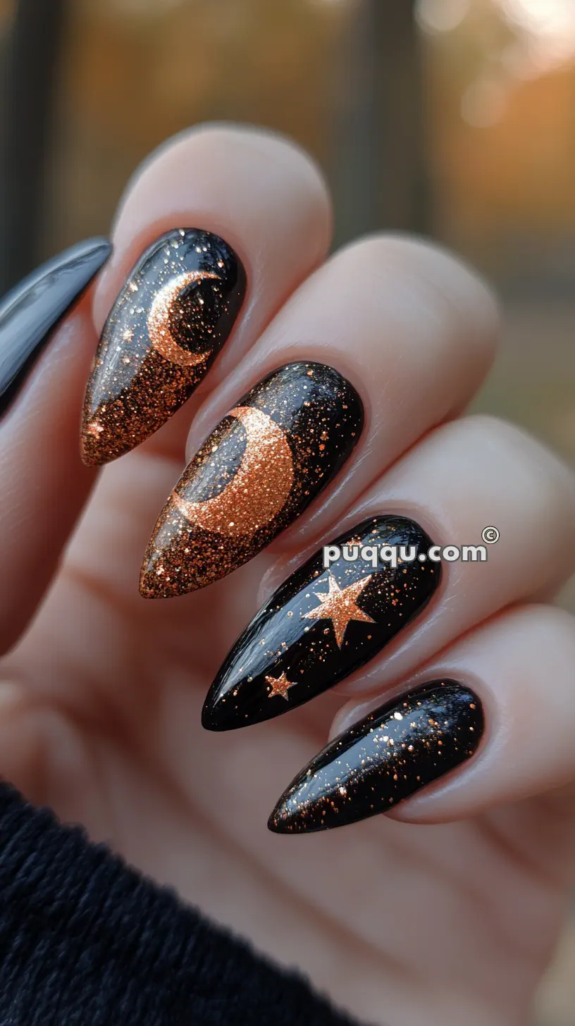 Black stiletto nails with sparkly orange moon and star designs