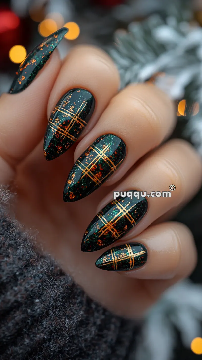 Hand with long black stiletto nails featuring orange and gold plaid nail art.