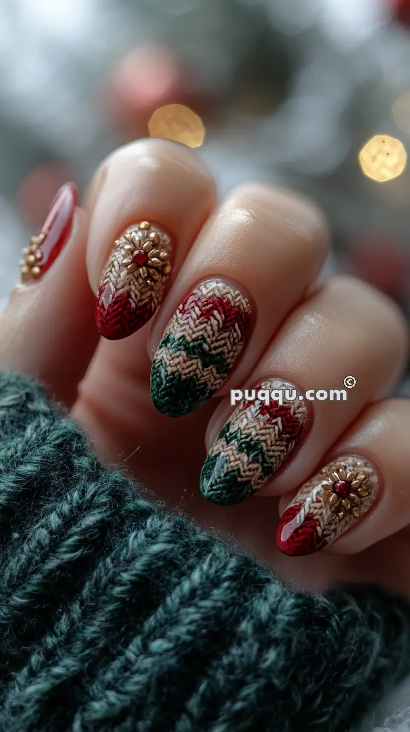 Nails with Christmas-themed designs featuring red and green knitted patterns and gold embellishments, held against a blurred background.