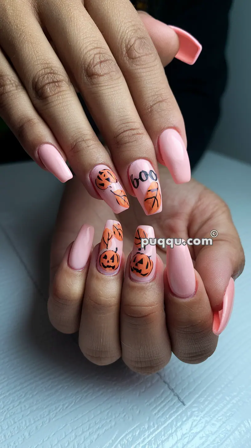 Pink acrylic nails with Halloween-themed designs, including pumpkins, autumn leaves, and the word "boo" on accent nails.