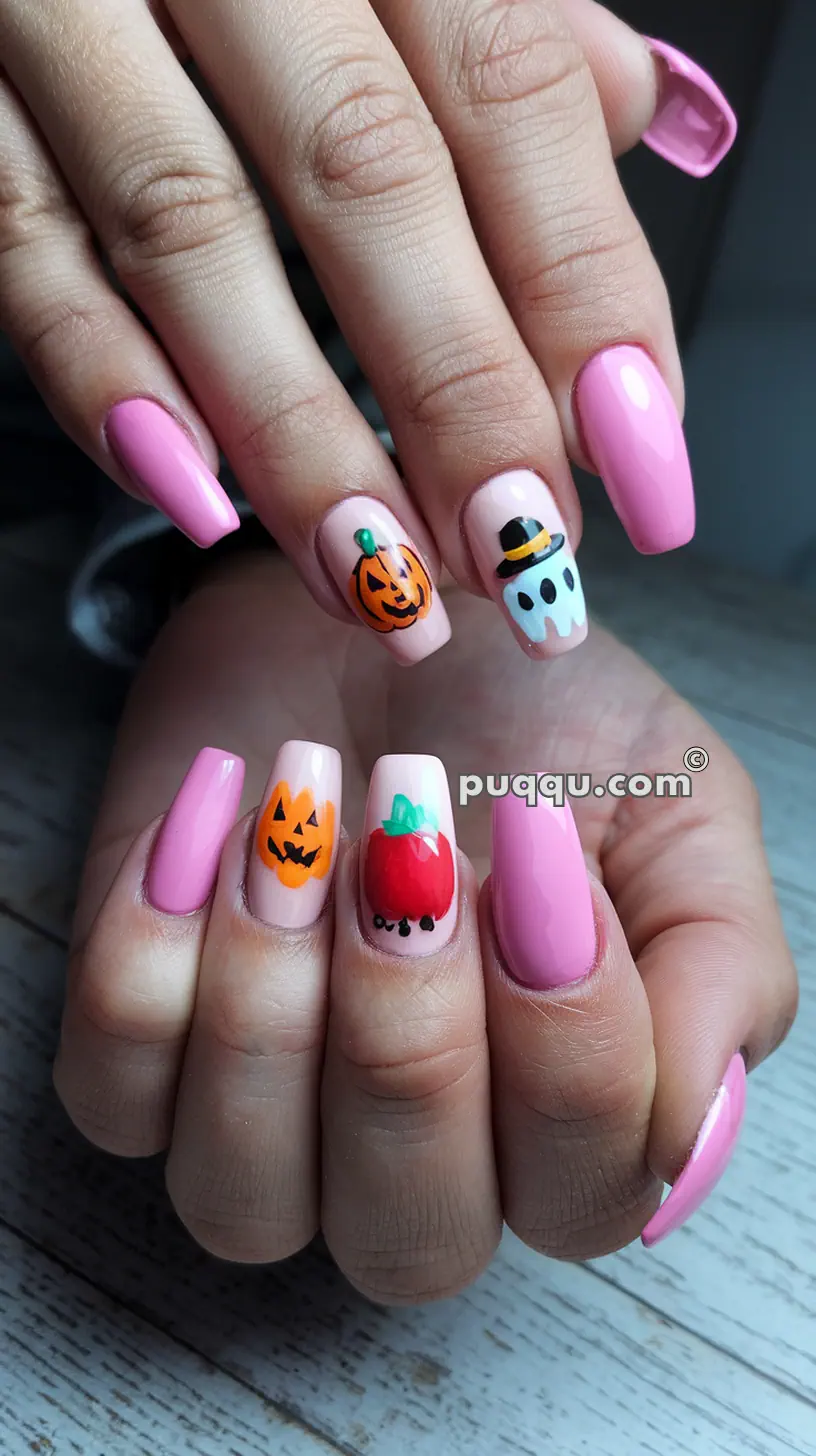 Hands with pink nail polish featuring Halloween-themed designs including pumpkins, a ghost, and an apple.