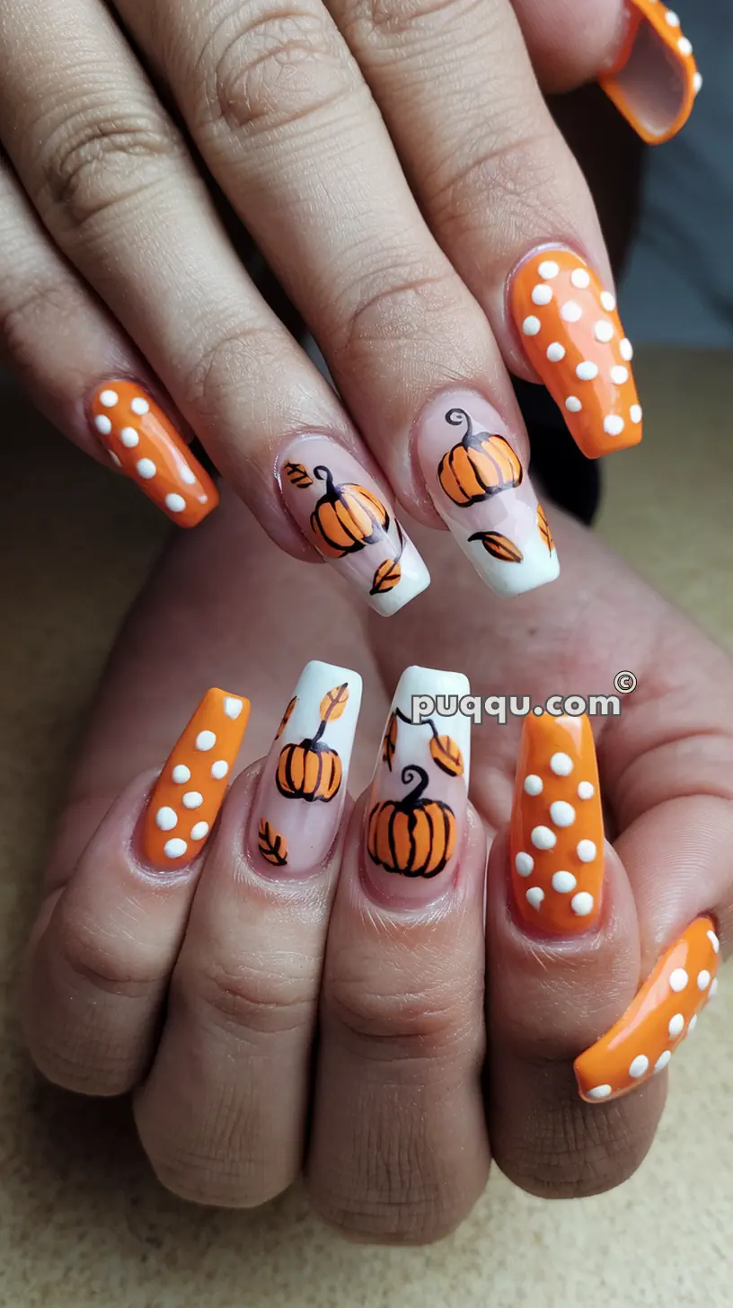 Close-up of hands with Halloween-themed nail art featuring orange pumpkins and white polka dots on an orange and nude base.